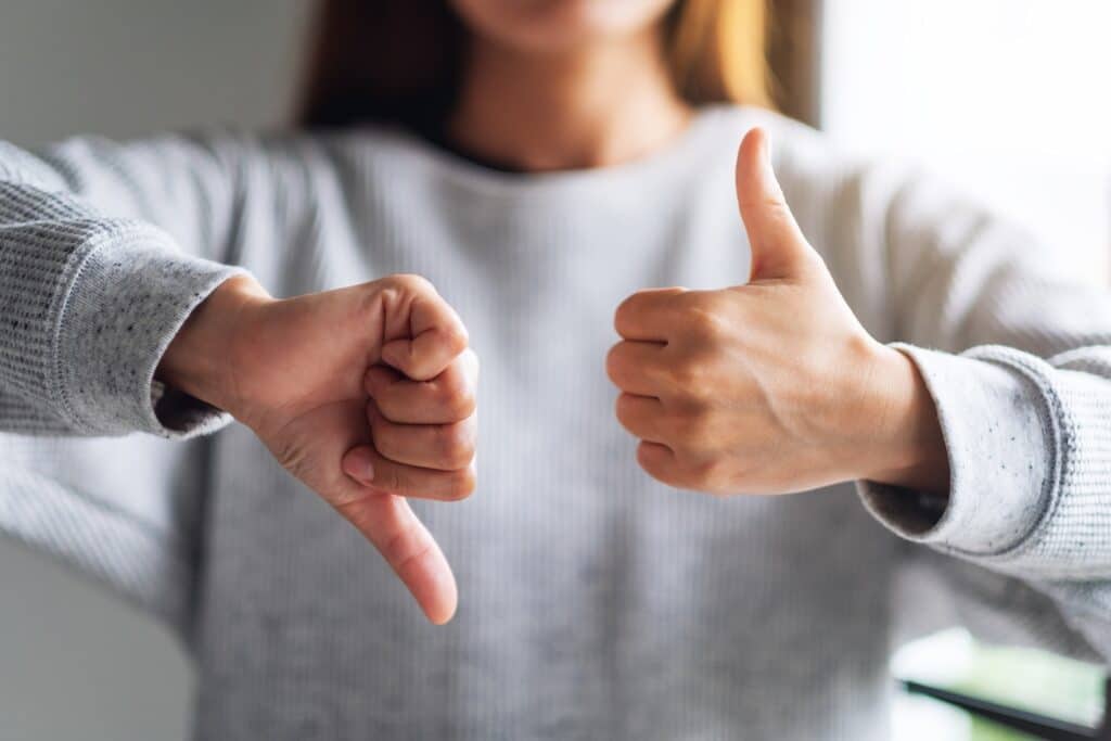 Closeup image of a woman making thumbs up and thumbs down hands